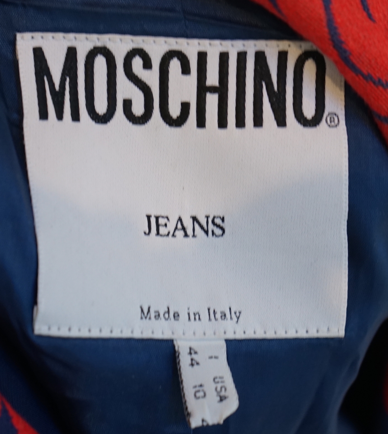 A Moschino lady's long blue and red jacket, a cream cotton embellished blazer and a cotton pair of floral trousers, blue and red jacket size 14, cream blazer size 12, trousers size: 10
